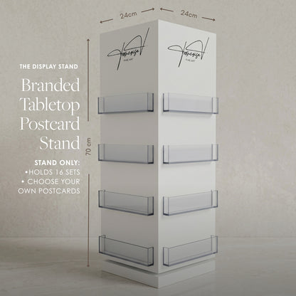 A freestanding white tabletop postcard display stand with six clear acrylic slots, shown with overlaid dimensions (24 cm top and bottom, 70 cm height) and text noting it holds 16 sets and allows custom postcards.